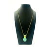 Delicate gold chain necklace with a faceted teal gemstone pendant and clear crystal stopper gemstone potion bottle necklace