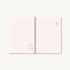 A soft pink ruled Studio Ghibli journal with delicate black line drawings of cartoon characters on the pages